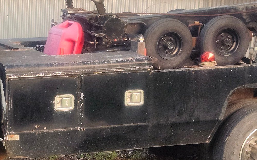Toolboxes, spare wheels and a fuel can on the bed of the wrecker.
